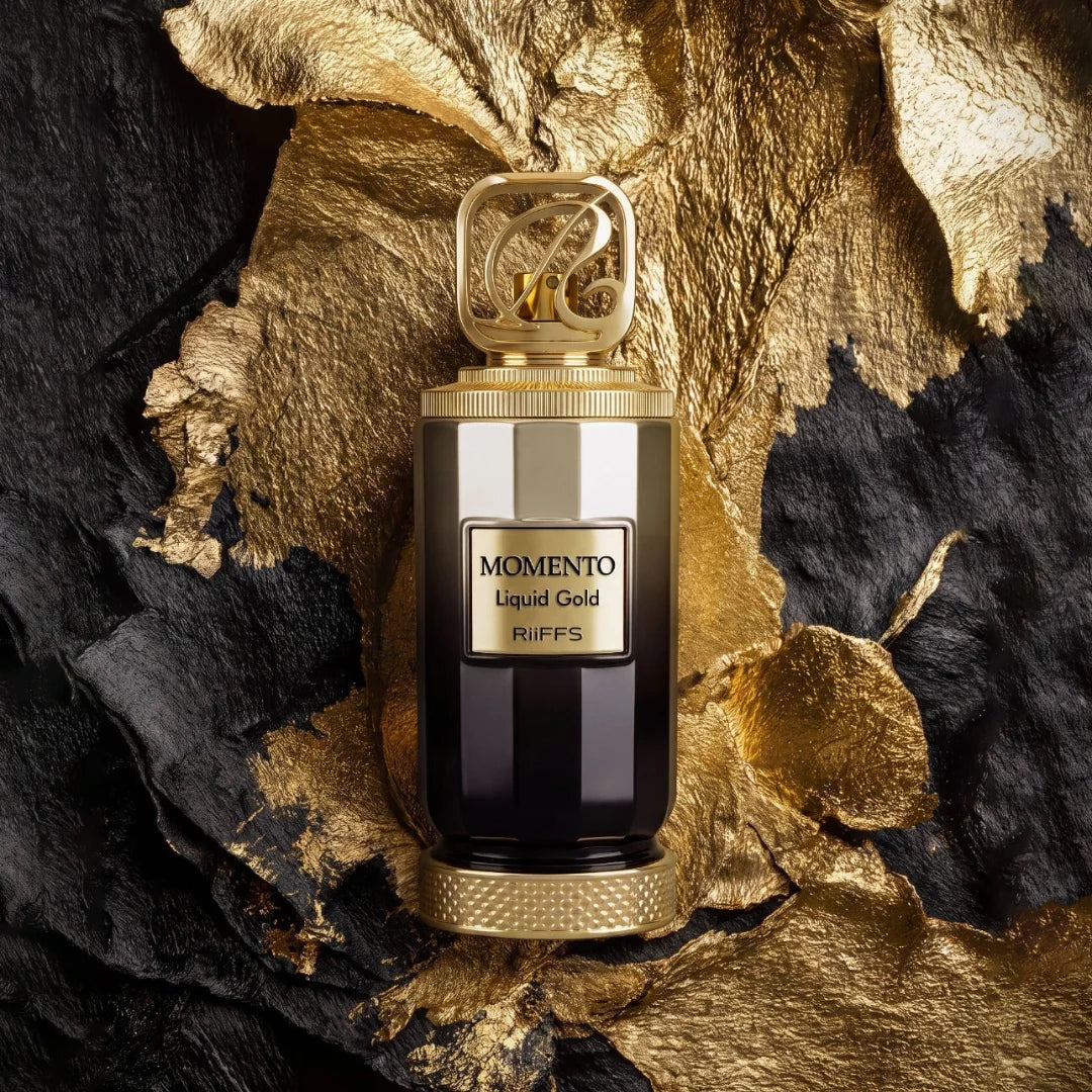 Momento Liquid Gold perfume bottle with a gold cap and black base, set against a textured black and gold background.